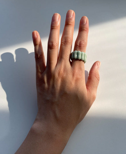 Mint textured ring on open hand against white backdrop